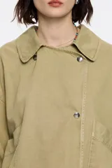 Cazadora corta color verde militar, cruzada con corte fluido, cuello camisero, manga larga recta con botón y cierre frontal con botonadura de presión. Incluye bolsillos plastrón inclinados.