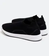 Championes negros de tela tejida, estilo slip-on, con suela blanca y detalles geométricos en los laterales.