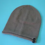 Gorro de lana color caqui, tejido a punto, con dobladillo y etiqueta con logo de la marca KristoBelga.