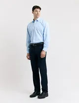 Traje de vestir color marrón topo, compuesto por saco de dos botones con solapa de muesca, dos bolsillos delanteros con solapa y un bolsillo superior. Pantalón de vestir con corte recto y bolsillos laterales. Incluye camisa blanca y corbata azul con lunares blancos.