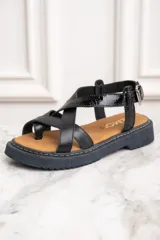 Sandalias de cuero negro con tiras cruzadas y hebilla al tobillo.