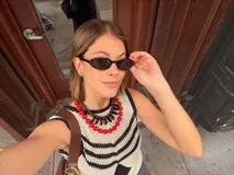 Chaleco calado negro con diseño de rayas diagonales rojas, beige y blancas.