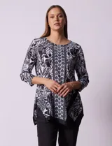 Blusa estampada en blanco y negro con diseño floral, de la marca Ruby Rd. Tiene cuello redondo con apliques de brillos, mangas 3/4 y ruedo asimétrico.