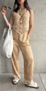 Conjunto beige con estampado de rombos blancos, compuesto por un chaleco con botones y pantalones de corte recto con bolsillos laterales. El pantalón tiene un diseño geométrico en el ruedo.