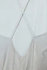 Vestido midi plateado confeccionado en hilo metalizado, con escote recto, tirantes finos y forro interior combinado.