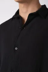 Camisa negra de lino con cuello clásico, manga corta y cierre frontal con botones.