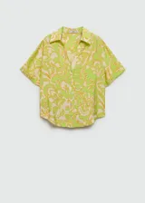 Camisa de manga corta con estampado floral en tonos verde, naranja y beige. Diseño oversize con cuello camisero y cierre frontal con botones.