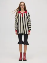 Chomba de corte oversize con cuello camisero, a rayas verticales en color marrón, lila y blanco. Tiene un logo bordado en el pecho y puños en color marrón.