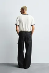 Pantalón de jean negro de corte amplio, con bolsillos delanteros y traseros, presilla portaherramientas en la pierna derecha y costuras a contratono.