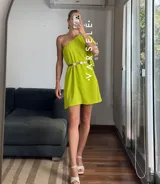 Vestido corto color verde lima, con escote asimétrico a un hombro, volado en el hombro y elástico en el borde superior.
