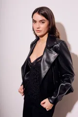Campera negra estilo biker confeccionada en cuero vegano, con cuello solapa, cierre asimétrico y bolsillos con cremallera.