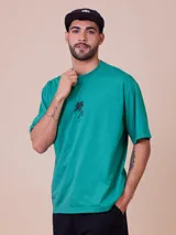 Remera verde esmeralda de algodón con corte relaxed, cuello redondo y estampado de flor en el pecho.