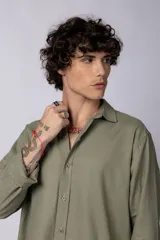 Camisa color arena de lino, manga larga, con cuello clásico y corte holgado.