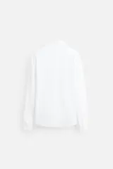 Camisa blanca de algodón, corte regular, con cuello italiano abierto, manga larga con puños abotonados y cierre frontal con botones.