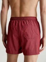 Bañador de largo medio color borgoña, con cintura elástica y cordón ajustable. Logo de Calvin Klein en el lateral.
