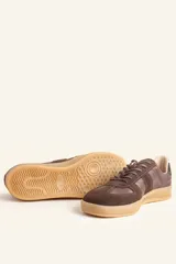 Zapatillas bajas de cuero color crudo con detalles en gamuza color beige y suela de goma color caramelo.