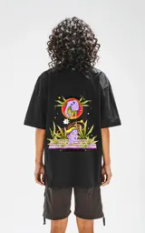 Remera negra de corte oversize con hombros caídos y cuello redondo. Estampado en la espalda con una mano que exprime un jugo sobre una persona rodeada de plantas de marihuana.