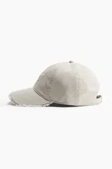 Gorra de béisbol color beige con aplique bordado de las letras "NY" en el frente y visera con efecto desflecado.
