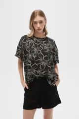 Blusa verde militar con estampado de flores blancas, de viscosa, corte holgado, cuello redondo y mangas cortas.