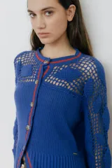 Cárdigan de algodón color crudo, con calce entallado y tejido acanalado. Presenta detalles de crochet hechos a mano, mangas con volados y vivos de color en cuello, puños y frente.