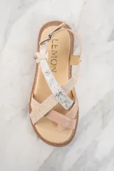 Sandalias con plataforma color beige y suela marrón. Tiras cruzadas en cuero color beige con textura y cuero plateado brillante.