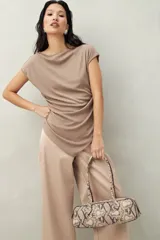 Top color beige de tejido acanalado, con cuello recto, sin mangas y terminación asimétrica en pico.