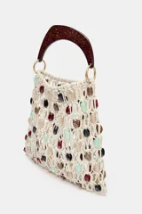 Bolso de mano tipo saca, tejido en red de color crudo, adornado con cuentas ovaladas de colores variados (rojo, negro, verde menta, beige). Posee un asa rígida de mano con acabado carey marrón oscuro.