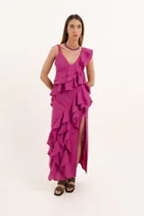 Vestido largo color fucsia de lino, con escote en V, breteles finos y falda con tajo lateral. Presenta volados verticales en el frente y espalda baja con tiras ajustables.