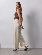Pantalón palazzo color crema, marca Nanette, con pretina elastizada, lazo de ajuste y bolsillos delanteros.