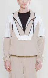 Anorak unisex color beige y blanco, con capucha, cierre de media cremallera y bolsillo tipo canguro.