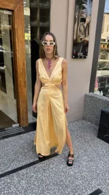 Vestido largo color durazno con escote pronunciado en V y aberturas laterales en la cintura. Presenta un drapeado frontal y falda con tajo lateral.