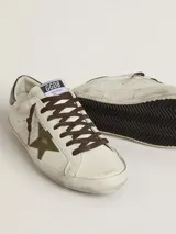 Zapatillas Golden Goose modelo Super-Star, de cuero color blanco envejecido con estrella de glitter verde y detalles en cuero color negro en el talón. Cordones marrones y suela de goma.
