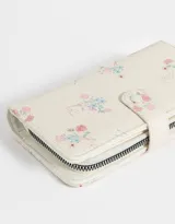 Billetera de cuerina color crema con estampado de flores y cierre con broche a presión.