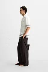 Pantalón relaxed fit color marrón oscuro confeccionado en tejido con mezcla de algodón y lino. Cintura elástica, bolsillos laterales y bolsillo trasero de plastrón. Perneras con pliegues frontales. Cierre en delantero con cremallera y botón.