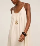 Vestido midi de color negro confeccionado en tejido de viscolino. Cuenta con breteles finos, escote redondo con pliegues frontales y un panel con volado en el ruedo.