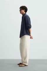 Pantalón verde oscuro de algodón con textura, corte recto, cintura elástica ajustable con cordón, bolsillos laterales y traseros de vivo.