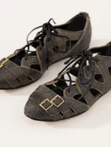 Zapato bajo acordonado de cuero texturado color negro, con diseño calado y aplique metálico con el logo de la marca.