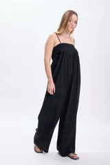 Mono largo negro con breteles finos y corte palazzo. Incluye cinturón ancho de cuero sintético con hebilla metálica y tachas.
