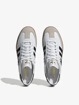 Zapatillas blancas de adidas con diseño atemporal, franjas laterales negras y puntera en forma de T.
