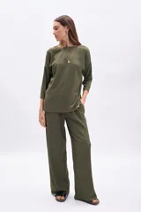 Pantalón de mujer color verde militar, de tiro alto y corte ancho (wide leg), confeccionado en tela con textura acanalada o plisada.