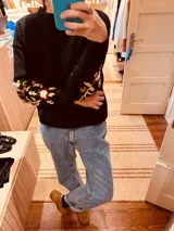 Sweater negro de lana con cuello redondo y mangas largas con bordado floral en puños.