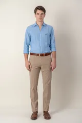 Pantalón de vestir color beige, de corte recto, con bolsillos laterales y traseros. Se ajusta a la cintura con cinturón de cuero marrón.