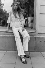 Pantalón de jean blanco, tiro alto, con pierna amplia y corte holgado. Presenta pliegues frontales y cierre de dos botones dorados.