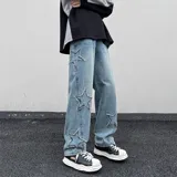 Jean de mezclilla celeste con apliques de estrellas bordadas en los laterales de las piernas. El corte es ancho y holgado, con elástico en la parte trasera de la cintura.