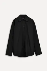 Camisa negra oversize de popelina de algodón, con cuello solapa, manga larga con puños abotonados, pinzas en la espalda y cierre frontal con botones.