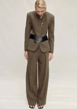 Pantalón de vestir color marrón, de corte ancho y tiro alto, con pinzas delanteras, bolsillos laterales y cierre frontal oculto.