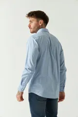 Camisa celeste a rayas rojas de hombre, manga larga, con bolsillo y logo bordado.