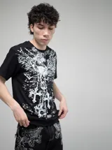 Remera negra de algodón con estampado frontal en blanco que incluye un cráneo con alas, cruces y detalles góticos. Corte oversize.