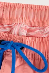Short de baño corto color coral con cintura elástica y cordón de ajuste azul.