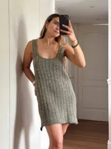 Vestido corto de tejido de punto color beige/dorado, con escote redondo y tirantes anchos. Presenta un tejido acanalado verticalmente con hilos de lurex que le dan brillo.